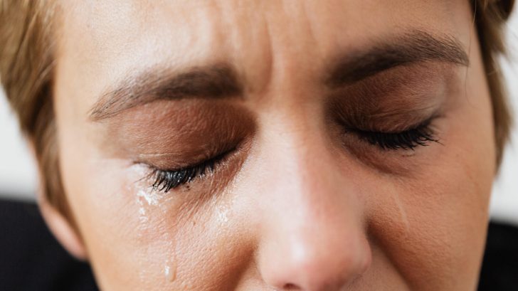 Tears on face of crop anonymous woman